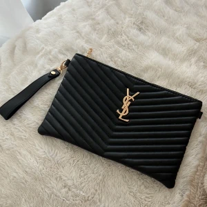 Svart/guldig clutch  - Säljer denna fina svart/guldiga clutch. Perfekt til nu somnaren. Tillkommer en kedja så man även kan ha den crossbody. Aldrig använd, nyskick. Säljer för 700 kr. Köparen står för frakten! 