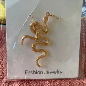 Örhängen med ormar, guldiga! Nya i obruten förpackning!  Fashion Jewelry Vet ej material  Är cirka 8-9 cm långa
