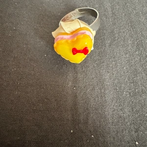 Gullig ring med en tårtbit på - Säljer denna gulliga ring som bara har använts en enstaka gång (och som sedan bara har legat i en låda). Den må kanske se lite smått rostig ut på insidan, men eftersom att ringen är nästintill helt oanvänd så är den ändå i fint skick.
