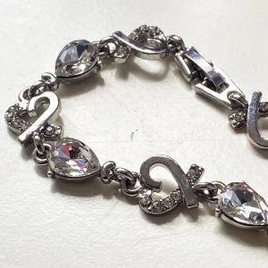 Armband  - Silverfärgat armband med gnistrande rhinestones och hjärtan   Alla rhinestones på plats  Okänt material  Ca 20 cm