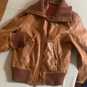 Brun läderjacka - Jättesnygg läderjacka!!! 💞💞💞Har lite ”skimmrigt” kopparfärgat tyg på insidan. Aning formsydd men märks inte för mycket!! Jätteskönt material inte säker om det är riktigt eller fake💕💕