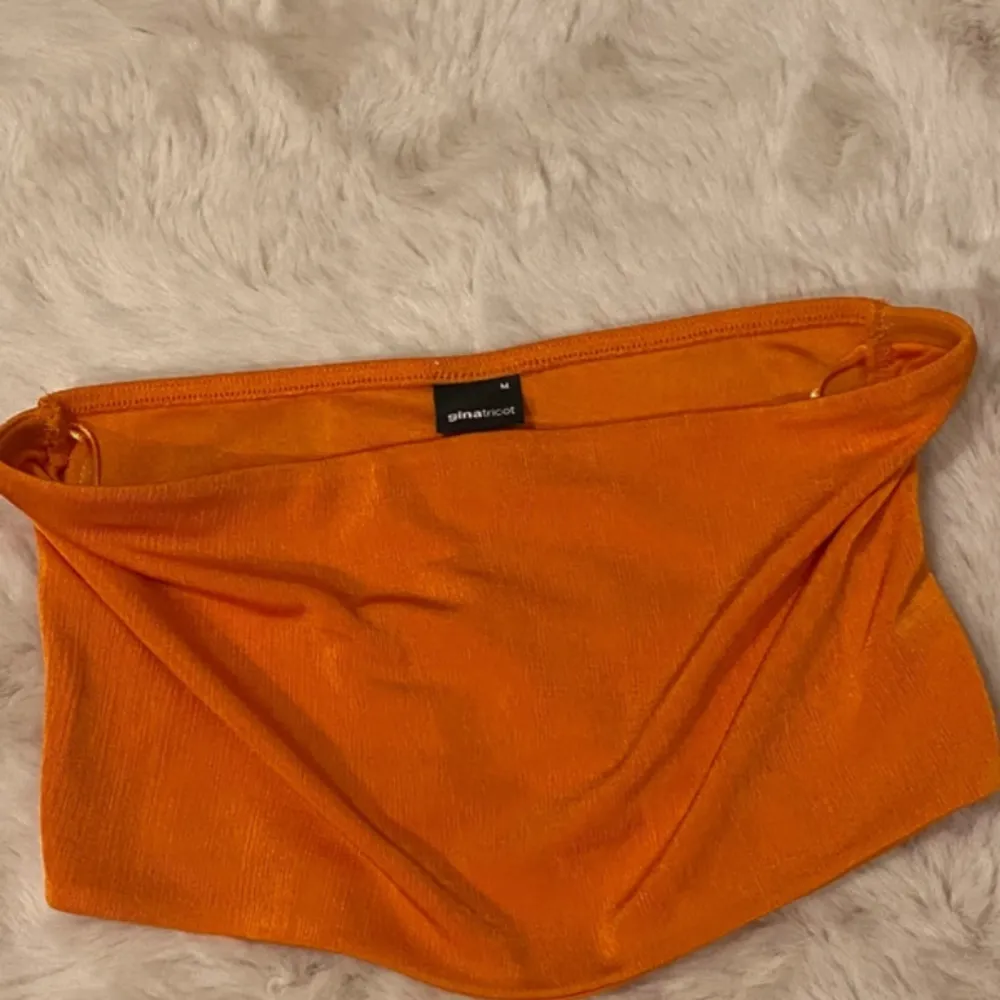 Tubtopp/bandau storlek M från Gina Tricot! Orange! NY Oanvänd  Vacker färg Se bild på bak där material finns på topp för att hålla den fast.  Stretch  Skimrande  Oanvänd  . Toppar.