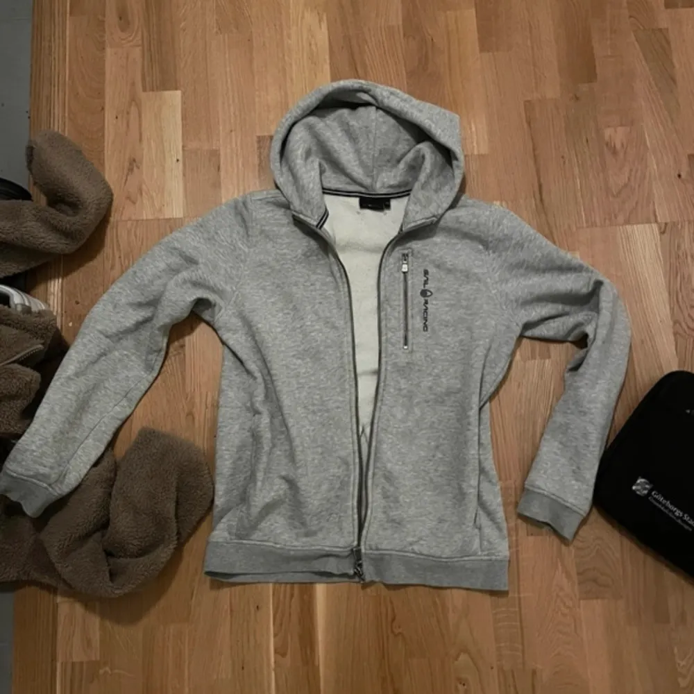 Jättesnygg grå zip-up sail racing hoodie som jag köpte för drygt 2 år sedan och nu inte använt på 1,5 år ungefär☺️lite slitningar på armbågarna men annars i mycket bra skick💕💕äkta! Nypris 999kr. Hoodies.