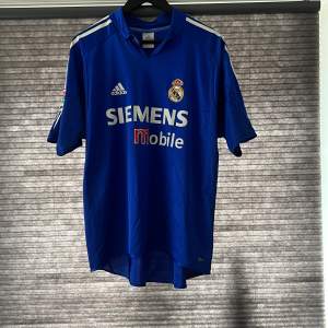 Real Madrid 2004/2005 tredje ställ!! Bra skick men det finns sprickor på båda axlarna och ett utsuddat namn på ryggen men annars i super bra skick.  Skriv till mig vid funderingar eller mer 😁🤩