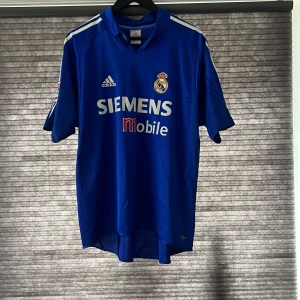 Real Madrid 2004/2005  - Real Madrid 2004/2005 tredje ställ!! Bra skick men det finns sprickor på båda axlarna och ett utsuddat namn på ryggen men annars i super bra skick.  Skriv till mig vid funderingar eller mer 😁🤩