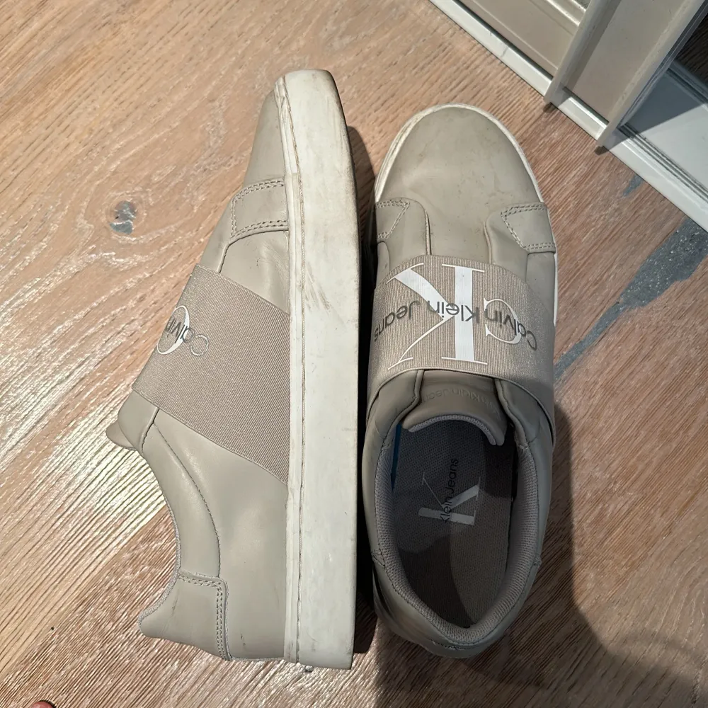 Ett par beiga Calvin Klein sneakers som är nästan helt i nyskick förutom under skon där man ser att de är lite annvända. Storlek 37 men de är stora i storlek så passar 38 också!😊. Kengät.