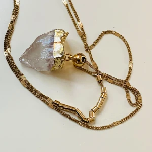 Halsband bergskristall  - Vackert guldfärgat halsband med dubbla kedjor och bergskristall som berlock  Längsta kedjan mäter ca 80 cm Den korta 64 cm