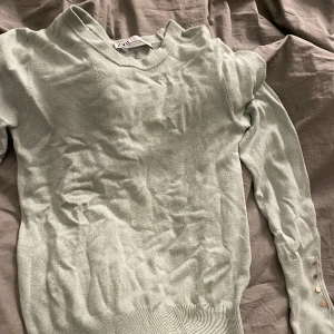 fin stickad tröja från zara - en fin stickad tröja med guld knappar som detalj på båda armarna. tröjan har dessvärre blivit skrynklig pga tvätt men går att stryka om man har strykgärn som jag tyvärr inte äger. inga fläckar och ingeb rost på knapparna!🩷