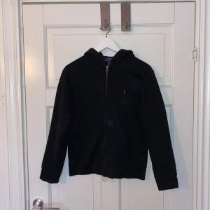 En fin svart Ralph Lauren zip hoodie! Jätte fint skick, inga skador. Jag säljer hoodie då den är för liten för mig. Hoodien passar upp till 165 cm lång!