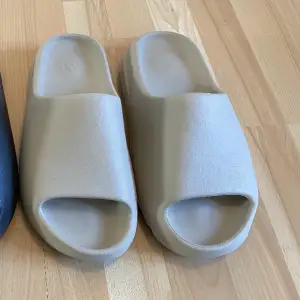 Ett par Slides behövs för varje person under sommaren och vad kan bli bättre än att ha ett par extraordinära Adidas YEEZY Slides i färgen beige.   1100 kr