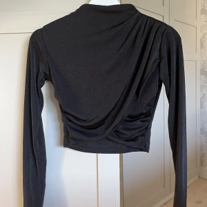 Topp från Nakd - Svart stretchig och croppad topp som går omlott framtill🖤