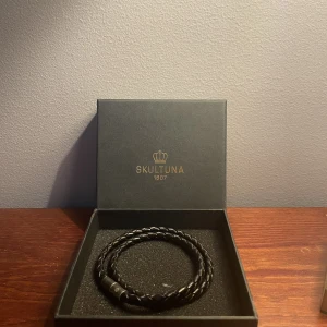 Skultuna Armband - Fint läderarmband från Skultuna, säljer pga att jag tröttnat på det. Köpt på Åhléns förra sommaren, har ej kvitto men kommer med en liten box. Sparsamt använd. 