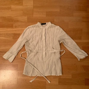 Vit blus🍂 - Blus i tunt tyg med diskreta ränder och knytband! Fin till sommaren! Knappar på framsidan och tre-kvarts-ärm:) Användes mycket i somras men nu måste jag rensa ur i min garderob:) Lägger ut snabbt nu men det är bara att skriva om man vill ha fler bilder🍂