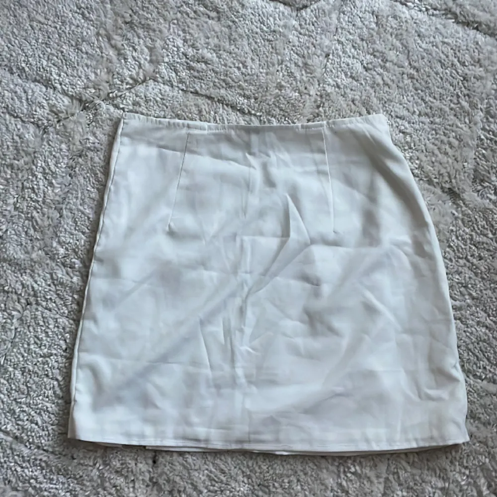 Kort vit kjol med slits, använd fåtal gånger men har sytt in den vid höften och på längden. . Kjolar.
