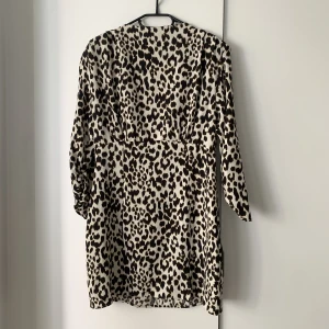 Leopardklänning Zara - Klänning i leopardmönster från Zara, storlek L. Har tyvärr aldrig fått chansen att använda denna så den är helt ny! Öppen i ryggen med dragkedja upp och sedan knappar i nacken