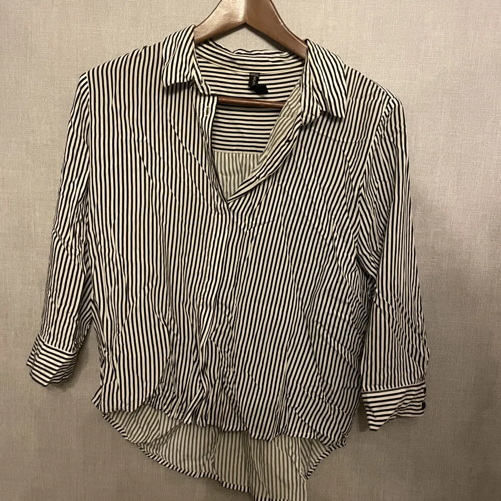 Vit/svart randig skjorta som är kort i ärmarna och lite längre bak till. Köpt i polen och är sparsamt använd . Blusar.