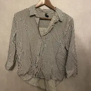 Vit/svart randig skjorta som är kort i ärmarna och lite längre bak till. Köpt i polen och är sparsamt använd 