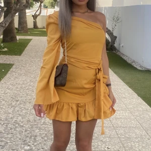 Gul Klänning - En armad klänning, som använts endast en gång. Storlek XS/34 Färgen är senapsgul och kan knytas med ett band som tillkommer. Finns i Södertälje men kan även fraktas.