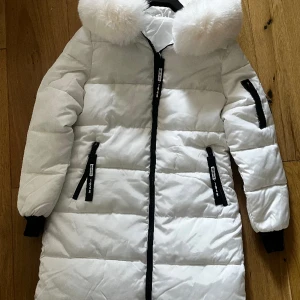 Vinterjacka dam - Vit fodrad vinterjacka. Går ner under rumpan.  Oanvänd. . Strl small. 