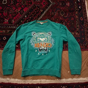 Kenzo tröja - Säljer en sjukt snygg grön Kenzo tröja i riktigt bra skick. Köpt på Nk för ca 1 år sedan. Säljer den för den är för liten. Nypris: ca 1200. Mitt pris 500