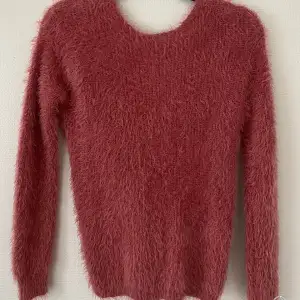 Stickad tröja i härlig hallon-rosa färg (svårt att få rätt färg på bilden)  Vriden/djup i ryggen 