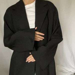 Svart kappa - Säljer denna svarta kappan i ull.  Köpt vintage men väldigt fint skick. Passar en S/M. Ner till anklarna på mig som är 165