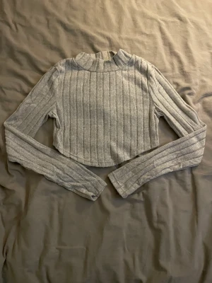 Grå långärmad tröja - Säljer denna långärmade tröjan då den är alldeles för liten för mig. Den är i storlek S men skulle säga att den passar storlek xxs eller kanske xs. Den är i ett väldigt mjukt meterial och är kortare i bak än fram. Aldrig använd endast provat!