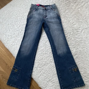 Bootcut Jeans - Midwaist bootcut jeans med unika kristaller och detaljer på benen och bakfickorna 🩷 Helt oanvända och köpta här på plick! Midja tvärs över: 32cm Innerbenslängd: 78cm