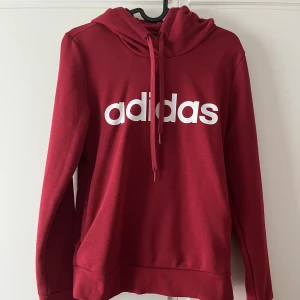 Röd hoodie  - Röd Adidashoodie med fickor på sidorna, använd få gånger, i bra skick, perfekt för höst och vinter.