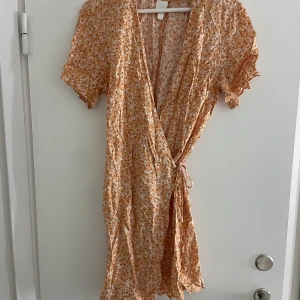 Orange blommig omlottklänning H&M - Orange, blommig omlottklänning från H&M. Storlek S, fint skick men behöver strykas. 🌸🌸⚡️FRI FRAKT⚡️