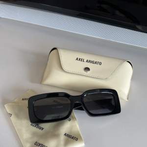 Upptäck den ultimata kombinationen av stil och funktionalitet med svarta Arigato solglasögon! Dessa solglasögon är en sann modeikon som inte bara skyddar dina ögon från solens strålar, utan också ger dig en sofistikerad och tidlös look.  Nypris: 1500kr