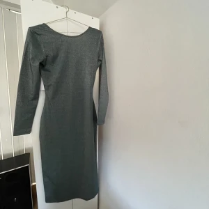 Glittrig maxiklänning med öppen rygg  - Säljer denna glittriga gröna klänningen med öppen rygg då den är för stor på mig. Aldrig använd , lappen är kvar