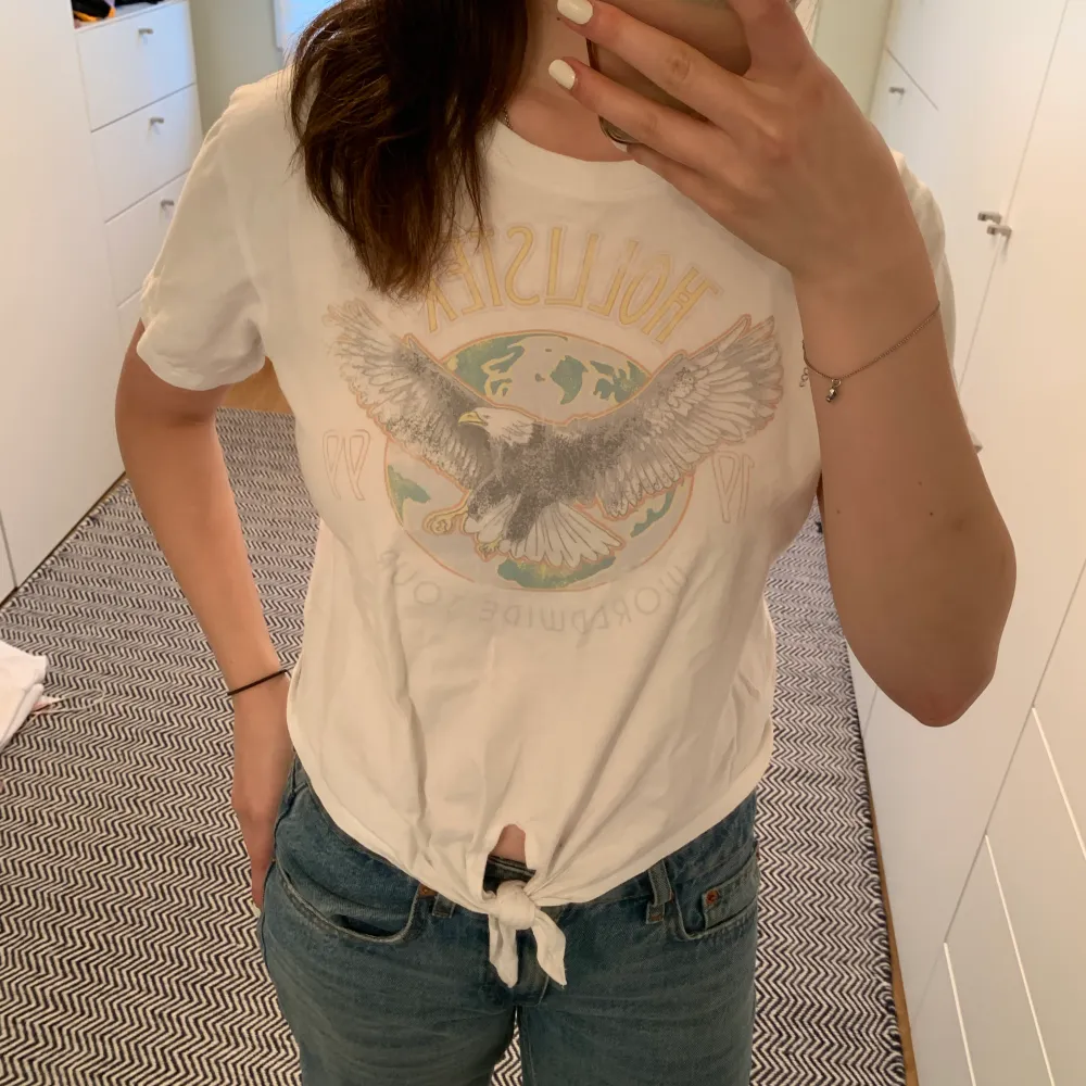 Säljer denna croppade T-shirt från Hollister med tryck och knytdetalj 💕😊. T-shirts.