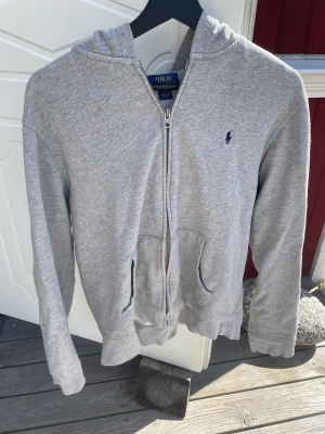 Ralph lauren zip hoodie  - Säljer denna Ralph lauren zip hoddie i grå pågrund av att den är för liten för mig. Den är i fint skick och sitter som st xl i barn storlek och ungefär xs-s i vuxen storlek.