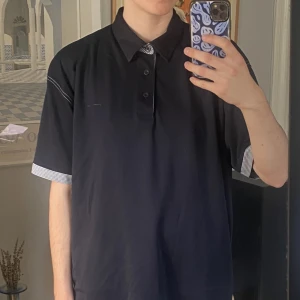 Piké T-shirt  - Fin piké tröja i gott skick. Fina rutiga detaljer vid kragen och ärmarna. Person på bild: 175 cm, S/M 