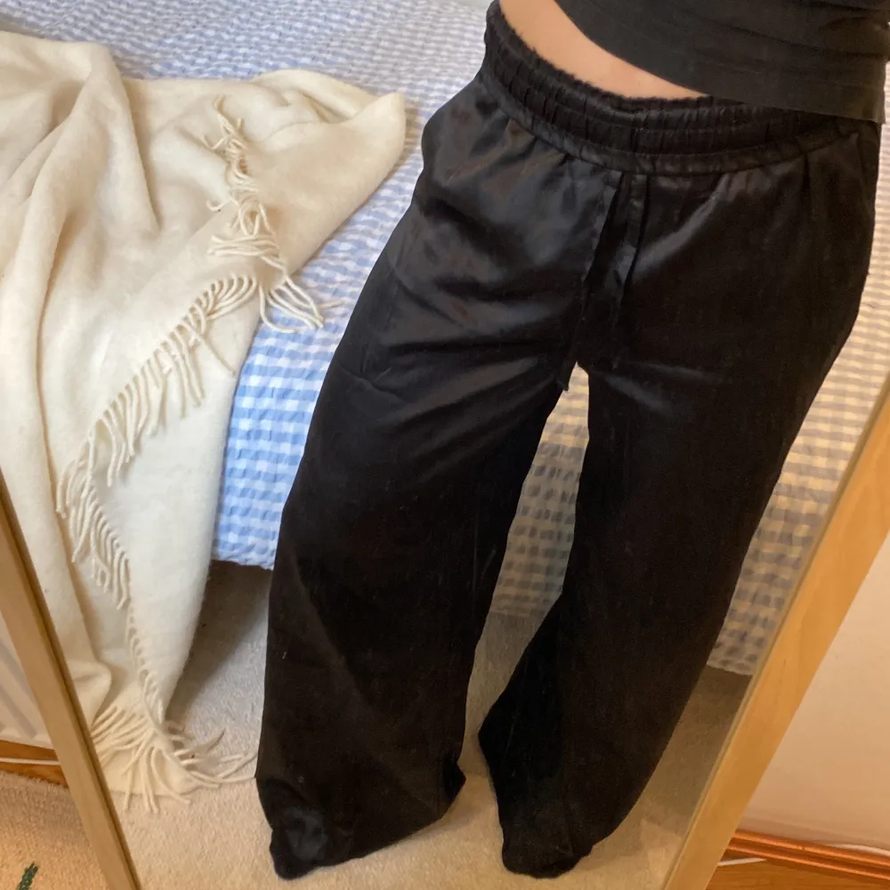 Svarta satinbyxor med vida ben som sitter perfekt i midjan. Byxorna är långa och helt i nyskick. Storleken är xs vilket ungefär är W28-32 L32 och de är ifrån Asos. Kan användas till vardagen eller passar perfekt som pyjamasbyxor . Farkut & Housut.
