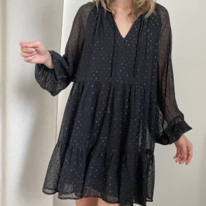 Klänning 34 - Svart fin volangklänning A-linjeformad. Storlek xs/34. Med glittriga prickar.  Oanvänd men har tagit bort lapparna :)