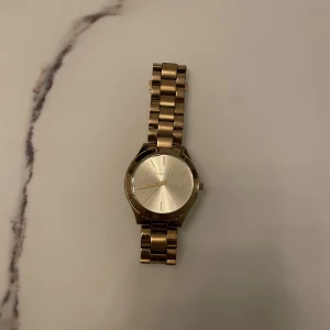 MICHAEL KORS  - - Äkta Michael kors klocka i guld.  - Fullt fungerande.  - Finns ytliga repor men inget som syns. - Nytt batteri.  - Rostfritt stål.  - Modell MK3179
