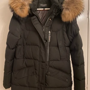 Hollies vinterjacka - Tjock vinterjacka, lång till över knäna ungefär, äkta päls använd en vinter säljs eftersom den blivit för stor på mig, bra skick och inte gått sönder storlek 38 men funkar även för 40. Priset kan diskuteras, jag står inte för frakten, för mer info skriv.