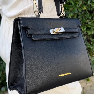 Borsa Ines nero  - Similpelle Dettagli in metallo tonalità oro L 28 cm x A 21 cm x P 10 cm Chiusura a scatto Tracolla in similpelle Dettaglio interno: tasca con zip, 2 tasche aperte Fodera 100% poliestere Include la sacca protettiva esterna Emily Morel, realizzata in raso, 