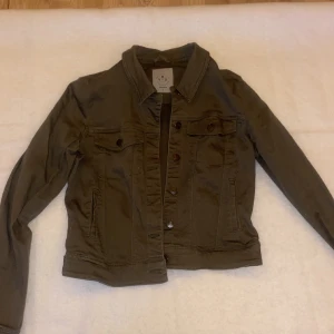 Grön jeansjacka - En väldigt fräsch militärgrön jeansjacka som är av kortare modell. Använd enstaka gånger men är utan skador och i väldigt bra skick! Storlek S