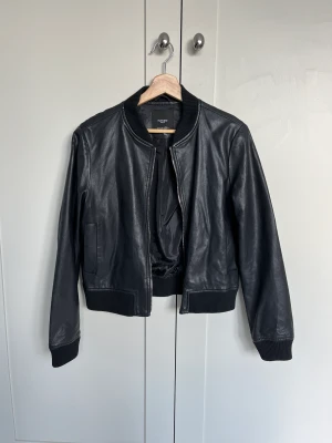 Skinnjacka - Bomberjacka i läderimitation, har sprickor i tyget kring axlarna, därav det låga priset. Storlek M men känns mer som S