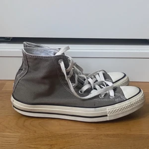 Gråa Converse stl 41 - Köpt second hand.  Gummit har gulant lite och har spruckit på flertal ställen har blivit lagade. Köparen står för frakten.