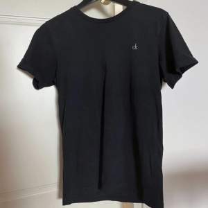 Svart Calvin Klein t-shirt med diskret tryck. Bredd axlar 42 cm. Bredd under ärmarna 46 cm. Längd 65 cm. OBS‼️ storlek 164/176 men använd som XS