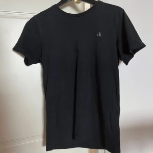 Calvin Klein t-shirt  - Svart Calvin Klein t-shirt med diskret tryck. Bredd axlar 42 cm. Bredd under ärmarna 46 cm. Längd 65 cm. OBS‼️ storlek 164/176 men använd som XS