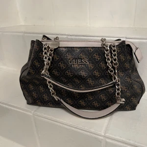 Guess handväska - Säljer denna skitsnygga handväska, den är lagom stor och man kan ha den närsom. Den är inköp på NK i Stockholm för 1499 kr och den är i fint skick