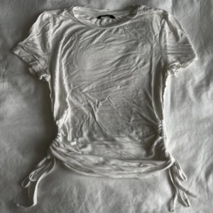 Tröja med dragsnören - Vanlig vit topp med dragsnörsdetaljer på sidorna. 