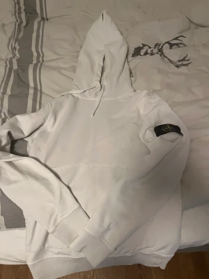 Stone island hoodie  - Fin vit Stone island hoodie i Stl S.  Är i bra skick utöver några små smutsfläckar som inte märks vid användning 
