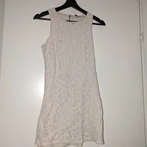 Elegant vit spetsklänning med liten öppning bak