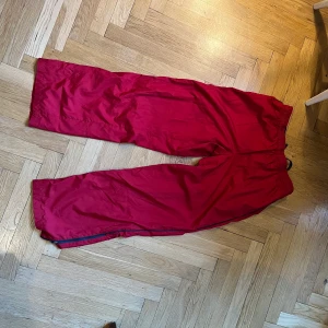 Röda vindbyxor - Röda vindbyxor som funkar perfekt för höst.  Dessa byxor är lite mer baggy vilket också tillför en extra gnutta swag. Meshtyg på insidan. Funkar också att träna i då de är väldigt luftiga och sköna.